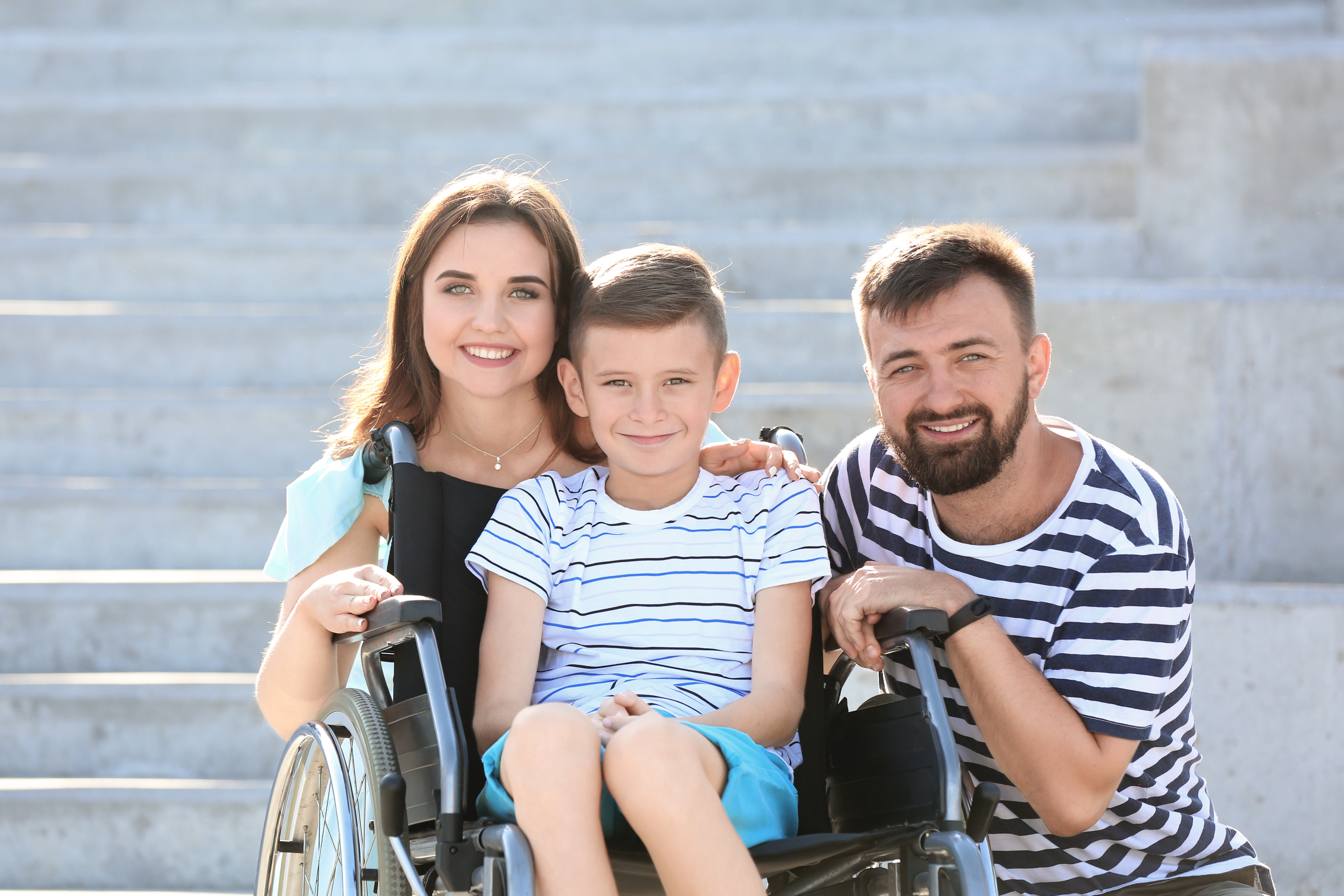 Teenage boy in wheelchair with his family outdoors