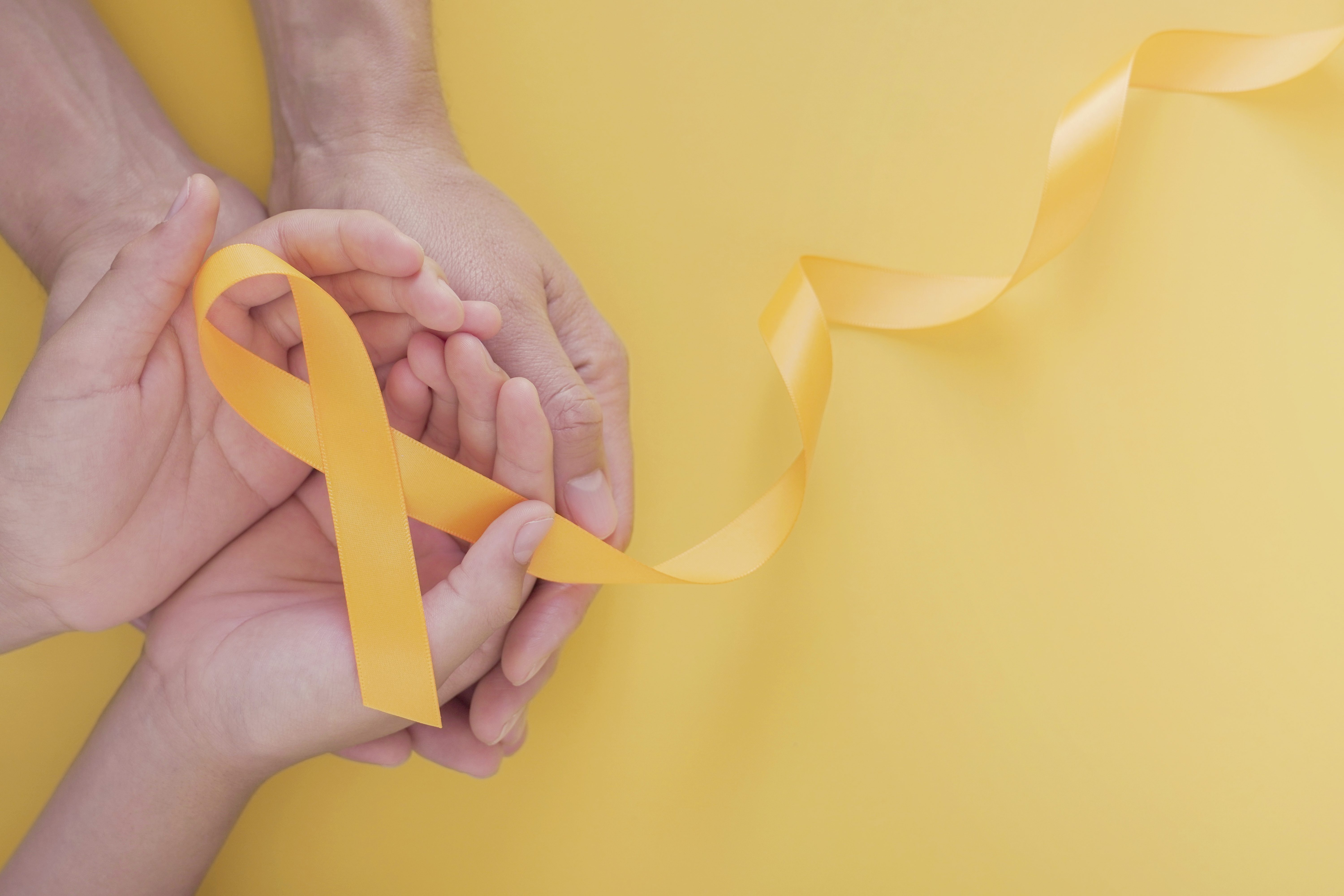adult and child hands holding yellow gold ribbon, Sarcoma Awareness, Bone cancer, childhood cancer awareness, world suicide prevention day, September Yellow