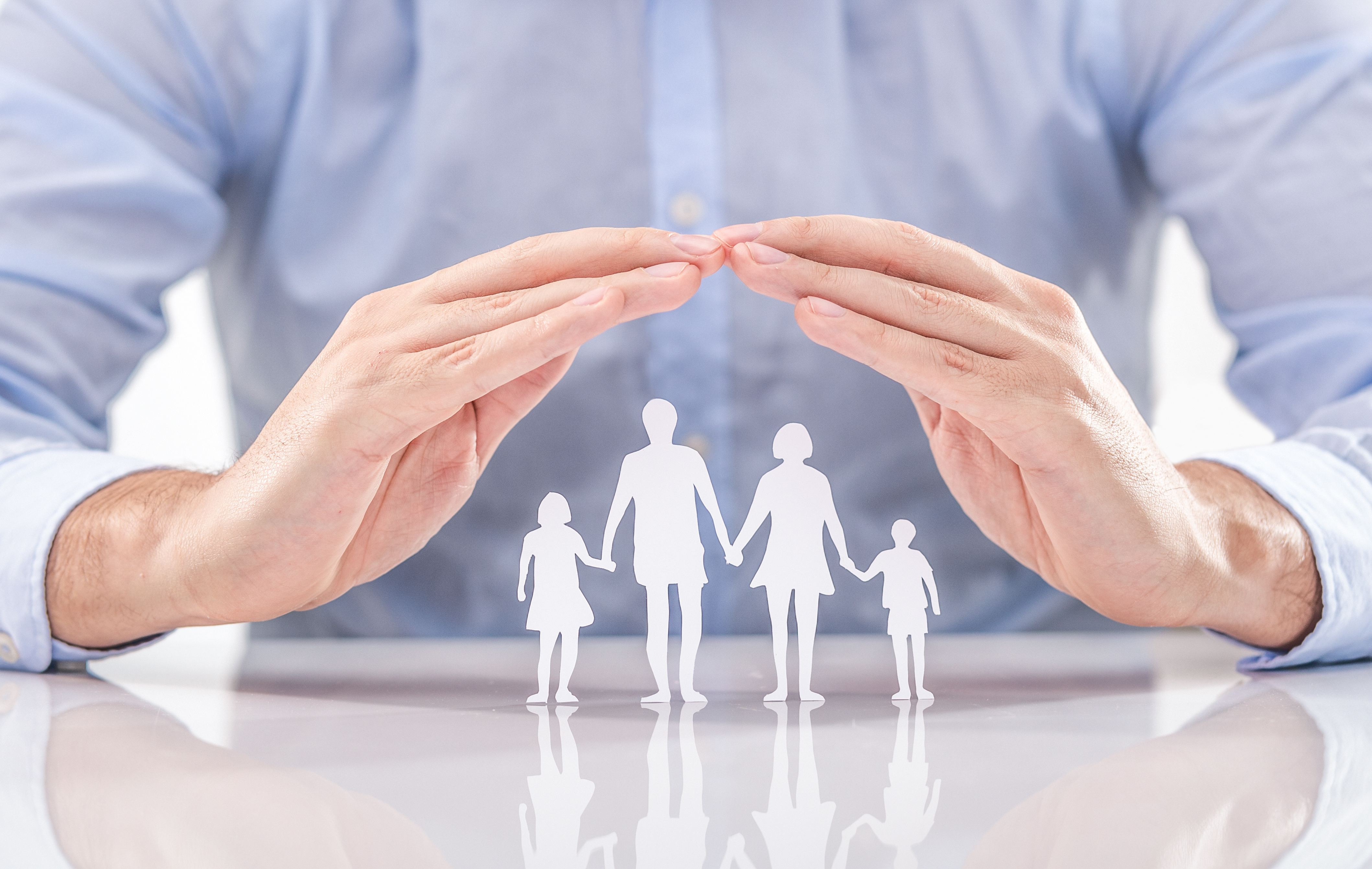 Family care concept. Hands with paper silhouette on table.