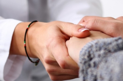 Friendly female doctor hold patient hand in office during recept