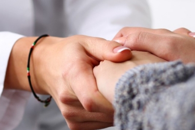 Friendly female doctor hold patient hand in office during recept